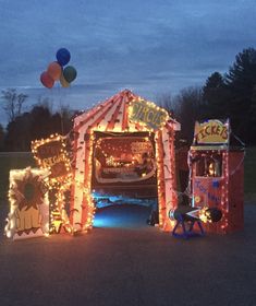 a car is parked in front of a circus tent with lights and balloons on it