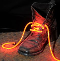 a pair of shoes with neon lights attached to them on a table in front of a black background