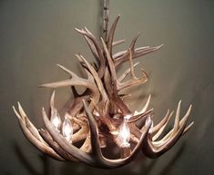 a chandelier made out of antlers hanging from the ceiling with lights on it