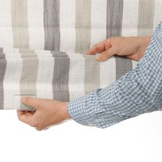 a person holding onto a striped blanket with their hand on the back of one of them