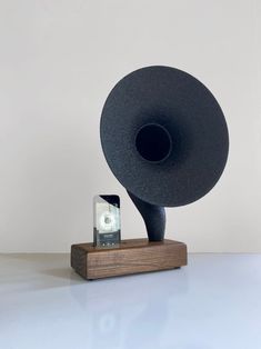 a black speaker sitting on top of a wooden stand next to a cell phone holder