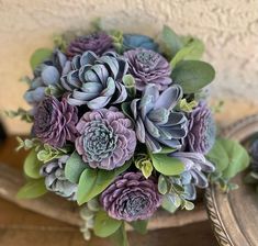 a bouquet of purple flowers sitting on top of a wooden table next to a mirror