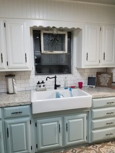 a white kitchen sink sitting under a window