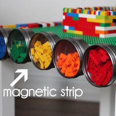 four tins filled with different colored legos sitting on top of a white table