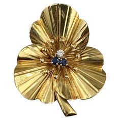 This is a gorgeous and rare Cartier Gold, Sapphire and Diamond Clover Flower Clip Brooch. The stunning jewel is an Antique brooch by Cartier dating to circa 1950. The rare clover motif jewel is 14 Karat Yellow Gold. It has three three-dimensional leaves with a gold beaded center. The clover is set with one diamond and two sapphires. The diamond has the brilliant white of the Cartier jewels. The sapphires are beautiful round faceted fine blue sapphires. The brooch is signed Cartier, 5144 and 14K. The clover has wonderful Retro Mid-Century Modern Design with clean yet festive lines. I love the joy of the Cartier jewels and this lucky clover is full of the joyful spirit of Cartier. The brooch is 1 1/2 inches (38mm) tall by 1 3/8 inches (33mm) wide. The diamond and sapphires are each approxima Cartier Gold, Vintage Closet, Clover Flower, Retro Mid Century Modern, Antique Brooches, Diamond Brooch, Flower Clip, Vintage Pieces, Sapphire Diamond