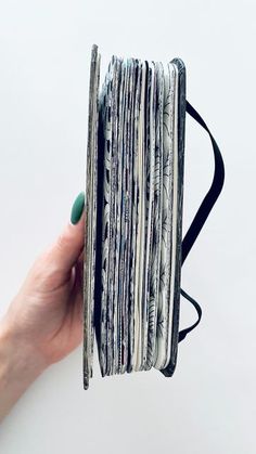 a hand holding a stack of folded magazines