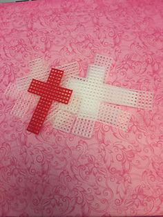 two red and white crosses on a pink background