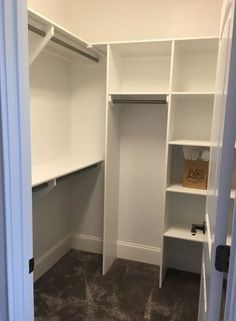 an empty walk in closet with white shelves and carpeted flooring on the ground