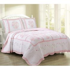 a pink and white quilted bed in a bedroom