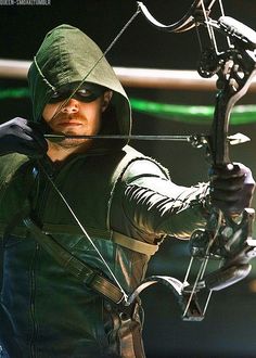 the arrow man is holding his bow and ready to shoot at something in the air