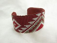 a red and white beaded bracelet sitting on top of a white cloth covered table