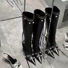 The Clara Buckle Detail Knee-High Boots are designed to make a bold fashion statement. Crafted in sleek black leather, these pointed-toe boots feature a modern, edgy look with buckle accents and a side zipper for easy wear. The stiletto heel adds height and sophistication, making these boots perfect for nights out or elevating your everyday style. The knee-high length elongates the legs, while the subtle buckle detailing adds a touch of character to this classic piece. Details: Black high qualit Party Leather Heeled Boots With Metal Feet, Leather Moto Boots With Pointed Toe, Leather Boots With Spikes For Evening, Leather Party Boots With Spikes, Chic Leather Moto Boots For Party, Pointed Toe Moto Boots With Rivets For Party, Leather Moto Boots With Rivets For Party, Party Moto Boots With Rivets And Pointed Toe, Leather Moto Boots For Winter Parties