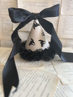 a paper party hat with black ribbon tied around it on top of an open book