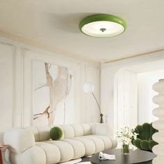 a living room filled with white furniture and green accents on the walls, along with a round coffee table