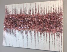 an abstract painting with pink and purple beads on white paper, hanging on a wall