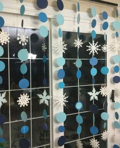 snowflakes hanging from the side of a window with blue and white decorations on it