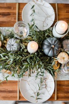 a wooden table topped with plates and candles