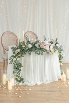 a table with candles, flowers and greenery is set up for a wedding reception