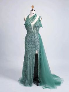 Elevate your evening wardrobe with this enchanting, emerald green gown that exudes sophistication and grace. Crafted with meticulous attention to detail, this dress features an intricate beading design that cascades down the bodice, adding a touch of shimmering allure. The one-shoulder neckline creates an asymmetrical elegance, drawing the eye to the décolletage and providing a modern twist on classic couture.The flowing skirt is designed from layers of soft tulle, offering a subtle transparency Green Embellished Ball Gown For Party, Embellished Green Ball Gown For Gala, Green Embellished Ball Gown For Wedding, Green Gown With Fitted Bodice For Banquet, Embellished Green Ball Gown With Fitted Bodice, Green Embellished Ball Gown With Fitted Bodice, Green Sequined Evening Dress For Banquet, Elegant Green Ball Gown With Sweep Train, Green Sequined Evening Dress For Banquets