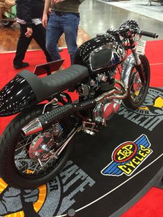 a motorcycle is on display at an event with people walking around the area behind it