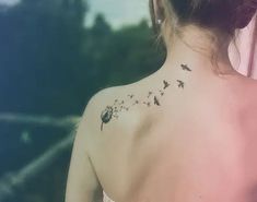 the back of a woman's shoulder with birds and flowers on her left side