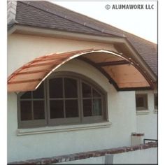 an awning on the side of a white house with brown shingles and windows