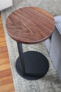 a round table with a wooden top on a rug in a living room area next to a couch