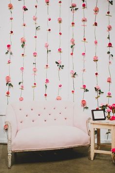 a pink couch sitting in front of a wall with flowers on it