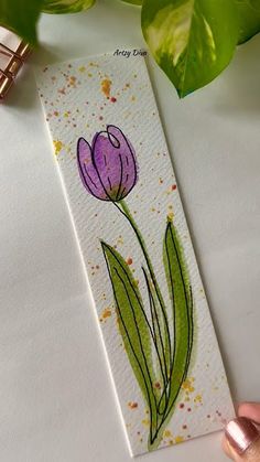 a hand painted bookmark with a purple tulip on it and gold flecks