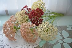 some flowers are sitting in a vase on a doily with white and red flowers