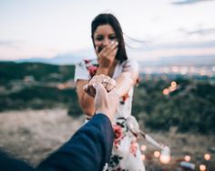 a man and woman holding hands with candles in the background at sunset or sunrise time