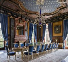 a dining room with blue chairs and a chandelier hanging from the ceiling above it