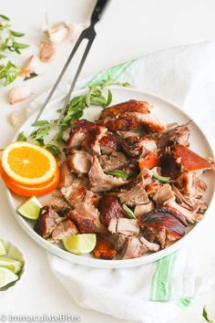 a white plate topped with meat next to an orange and green garnish on top of a table