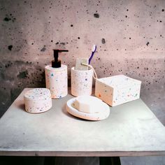 a table with soap, toothbrushes and other items on it in front of a concrete wall