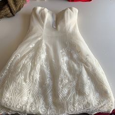 a white dress sitting on top of a table next to crochet and yarn