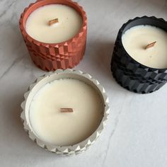 three candles sitting next to each other on a white counter top with one candle in the middle