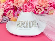 a bridal hat with the word bride written on it sitting in front of flowers