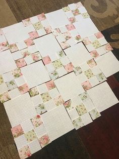 several pieces of paper are laid out on the floor to be cut into squares with scissors