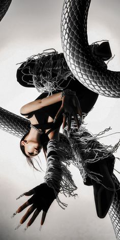 a woman with her hands in the air and two snakes on her back, both wrapped around her body