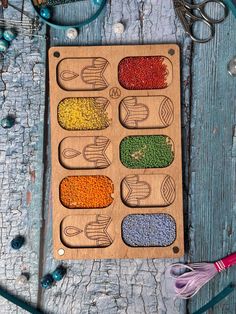 a wooden tray with beads and scissors on it