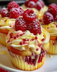 cupcakes with raspberries and cream frosting on a white plate