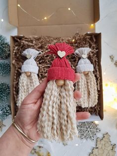 a hand holding a small doll with long blonde hair and a red knitted hat