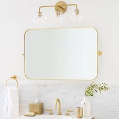 a bathroom with marble countertops and gold fixtures, including a large mirror above the sink