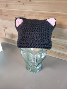 Black Cat Beanie with Pink Ears Hat for Kids and Adults This warm and soft cat beanie will keep you and your kid's head warm this winter.  The cat beanie is black with soft pink ears.  The kitty beanie is knit with soft acrylic yarn.  You can customize the colors of this beanie.  Just message me with the colors you're looking for. This cat beanie fits kids and adults.   This item is made special for you. If concerned about time, please inquire about my current back log or select priority mail at checkout and your order will be moved to the top of my queue.  With over 40 years of knitting and crochet experience, my products are high quality, well made and professionally finished. Check out my store for other fun custom hats.  All items can be customized for you.  I create them personally in Novelty Cat Ears Winter Hat, Winter Novelty Cat Ears Hat, Novelty Cat Ears Costume Hats For Winter, Black Cat Ears Hat With Cat Design, Black Cat Design Hat With Cat Ears, Black Hat With Cat Ears And Cat Design, Adjustable Cat Ears Winter Hat, Black Novelty Beanie One Size Fits Most, Novelty Black Beanie, One Size Fits Most