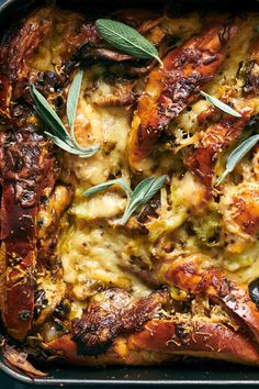 a casserole with meat, cheese and herbs on it in a baking pan