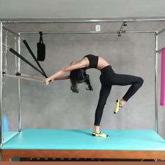 a woman in black shirt doing aerial acrobatics on blue mat with dog