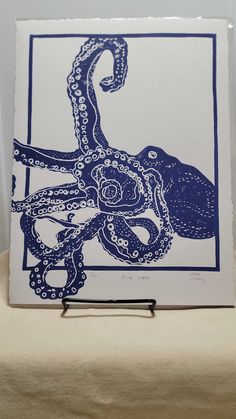 an octopus is shown in blue ink on a white card with a black string attached to it