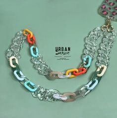 a multicolored chain necklace is displayed on a light green surface with the words urban style written below it