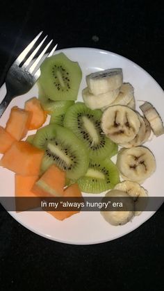 a white plate topped with cut up fruit next to a knife and fork on top of a table