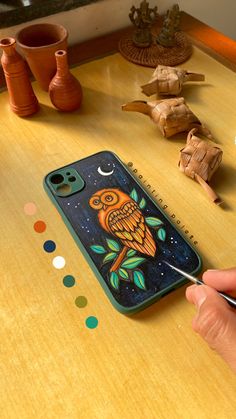 a person is drawing an owl on a phone case with markers and paintbrushes